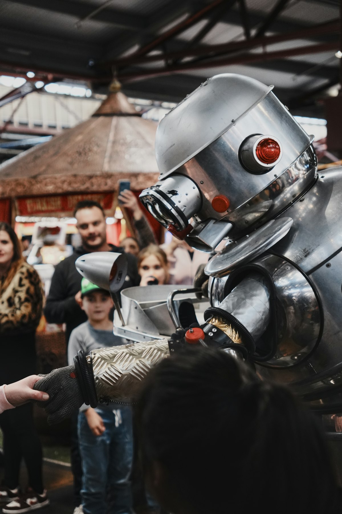 An orange humanoid robot interacting with people at an exhibition