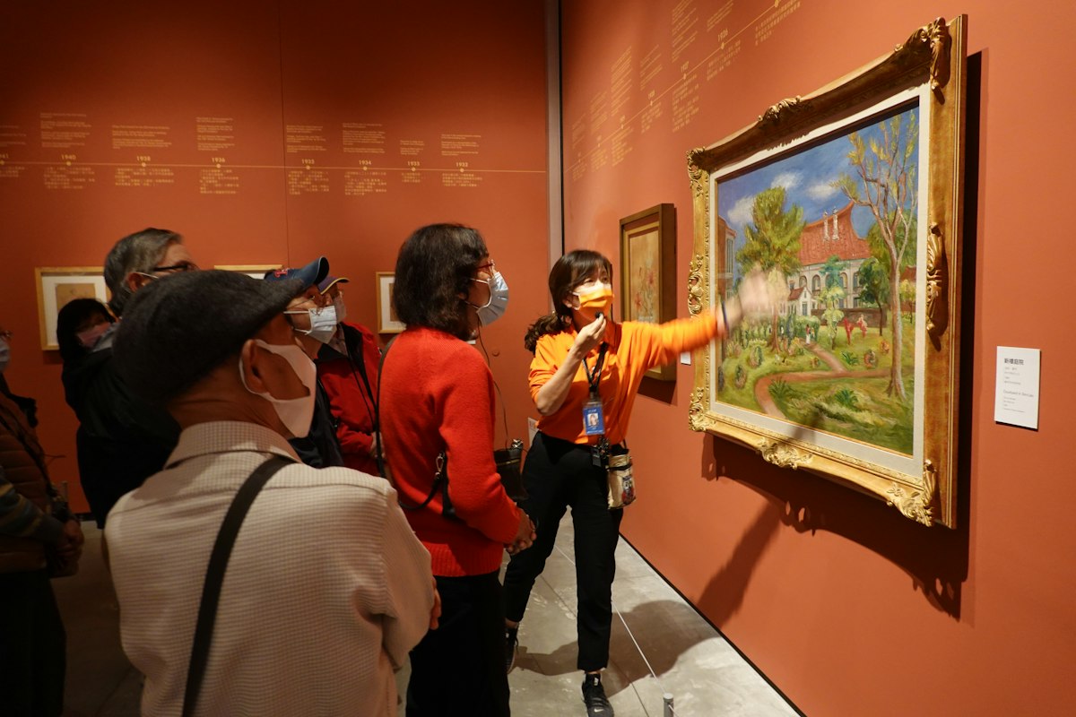 A human guide discussing artwork with museum visitors