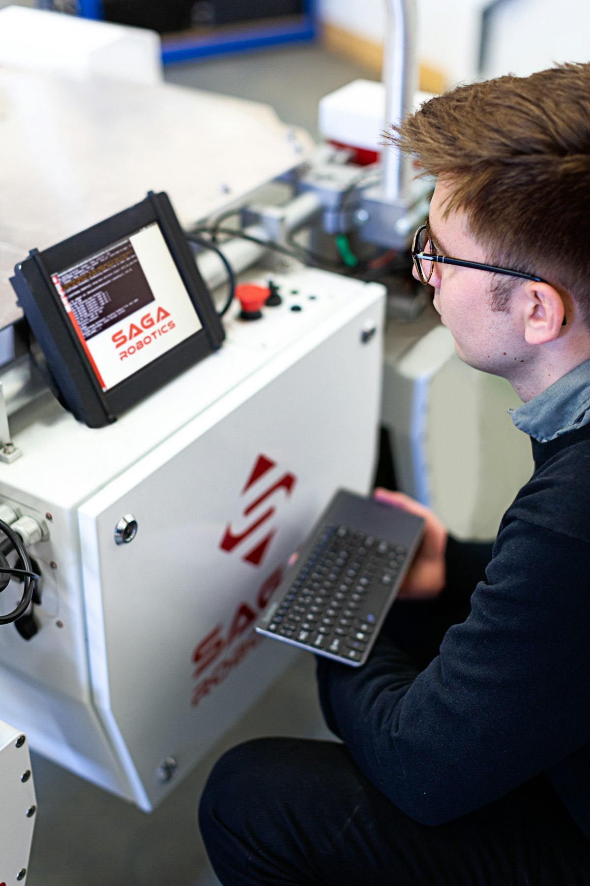 A robotics engineer working at a computer in a workshop
